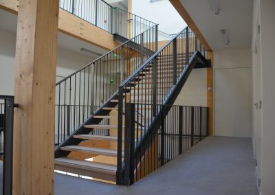 Escalier droit à marches en bois et garde-corps à barreaux en acier