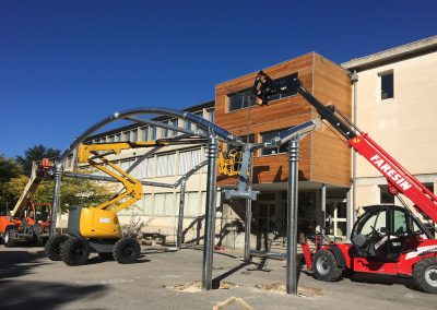 Installation par grue de la noue centrale de la pergola acier et toile micro-perforée